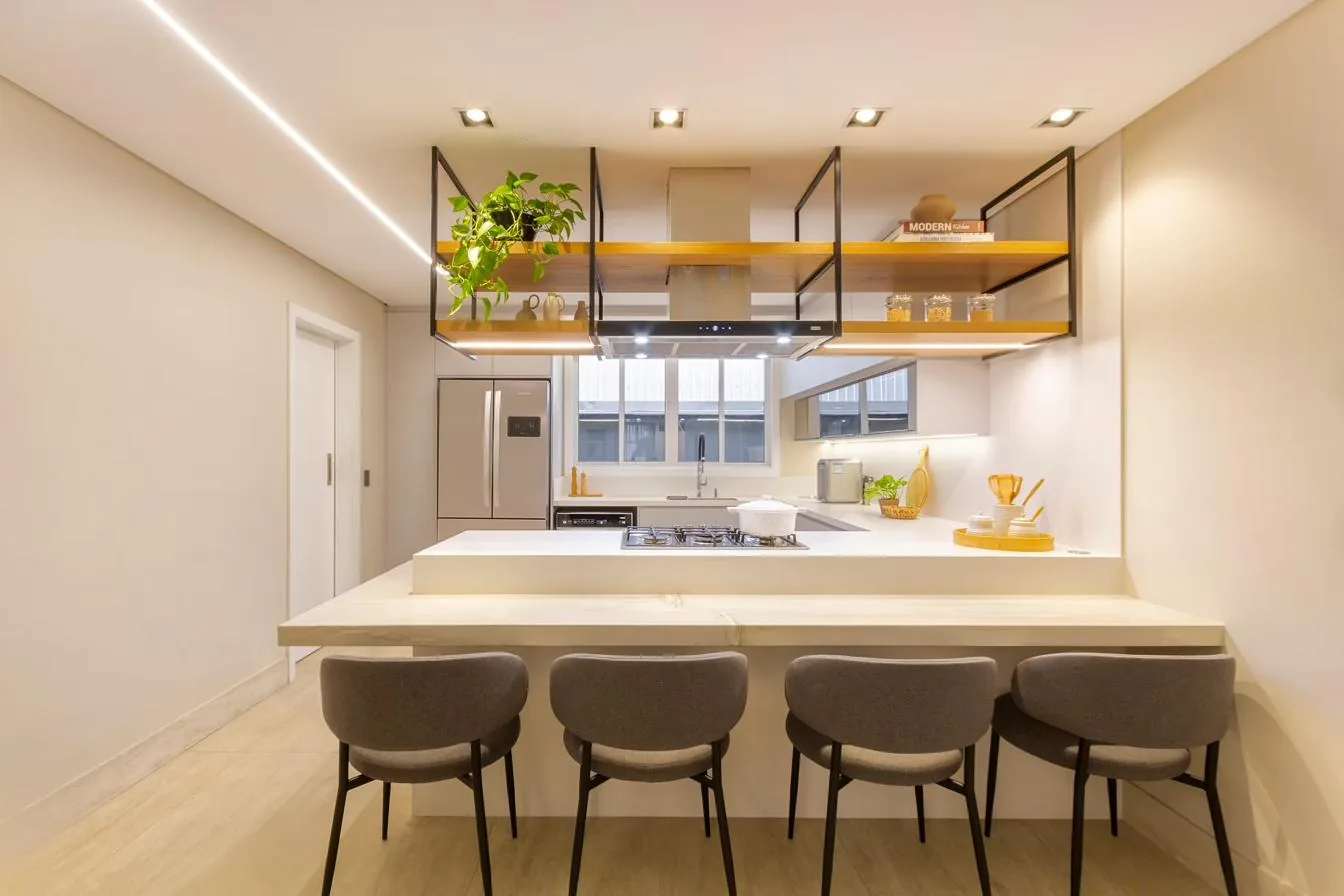 Cozinha com bancada em porcelanato, prateleiras suspensas com iluminação e banquetas estofadas