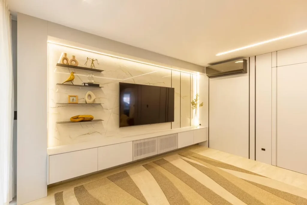 Painel de TV em porcelanato com veios dourados, prateleiras metálicas e iluminação embutida